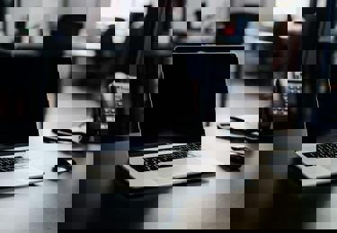 En dator på ett skrivbord bredvid en telefon.